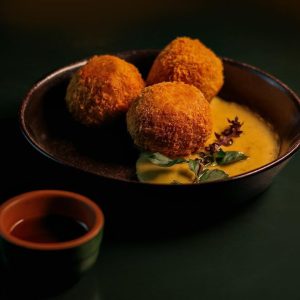 Apresentamos+nosso+Arancini.+Também+conhecido+como+COXINHA+ITALIANA,+feito+com+arroz+arbóreo,+recheado+com+carne+seca+e+queijo+nicola,+acompanhado+com+purê+de+banana+da+terra+e+molho+redução de limão rosa.+Uma+verd